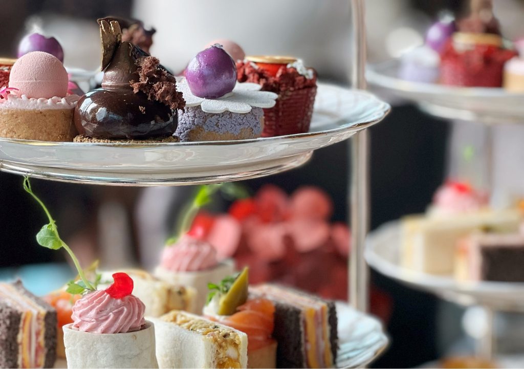 Celebration afternoon tea at Holbrook Manor in Somerset, featuring a tiered stand with assorted cakes, pastries, and sandwiches, served with tea in an elegant dining setting.